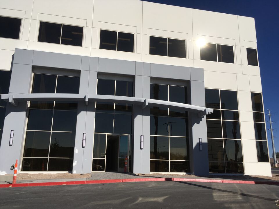 Two-story white commercial building with tall windows under a blue sky