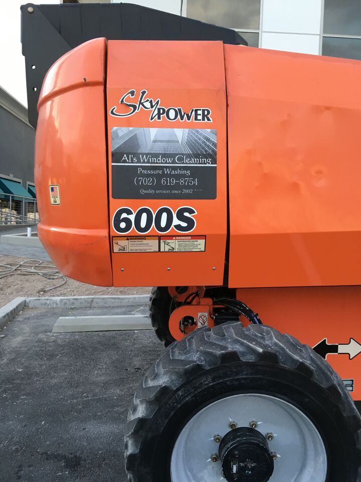 Orange boom lift carrying the Al’s Window Cleaning decal