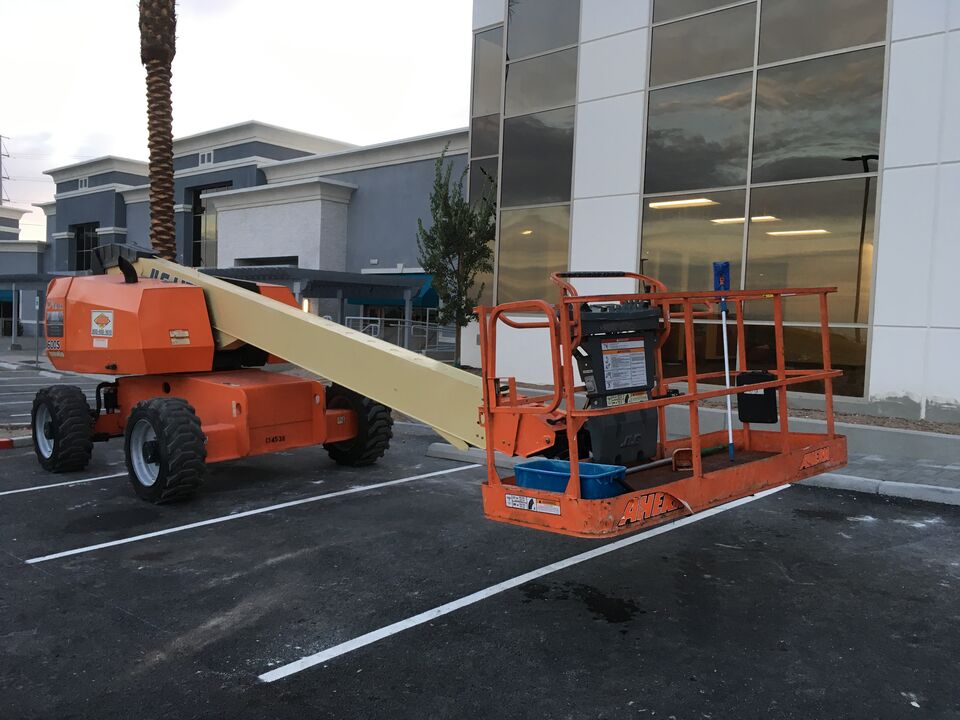 Boom lift set up beside the glass wall of an office building